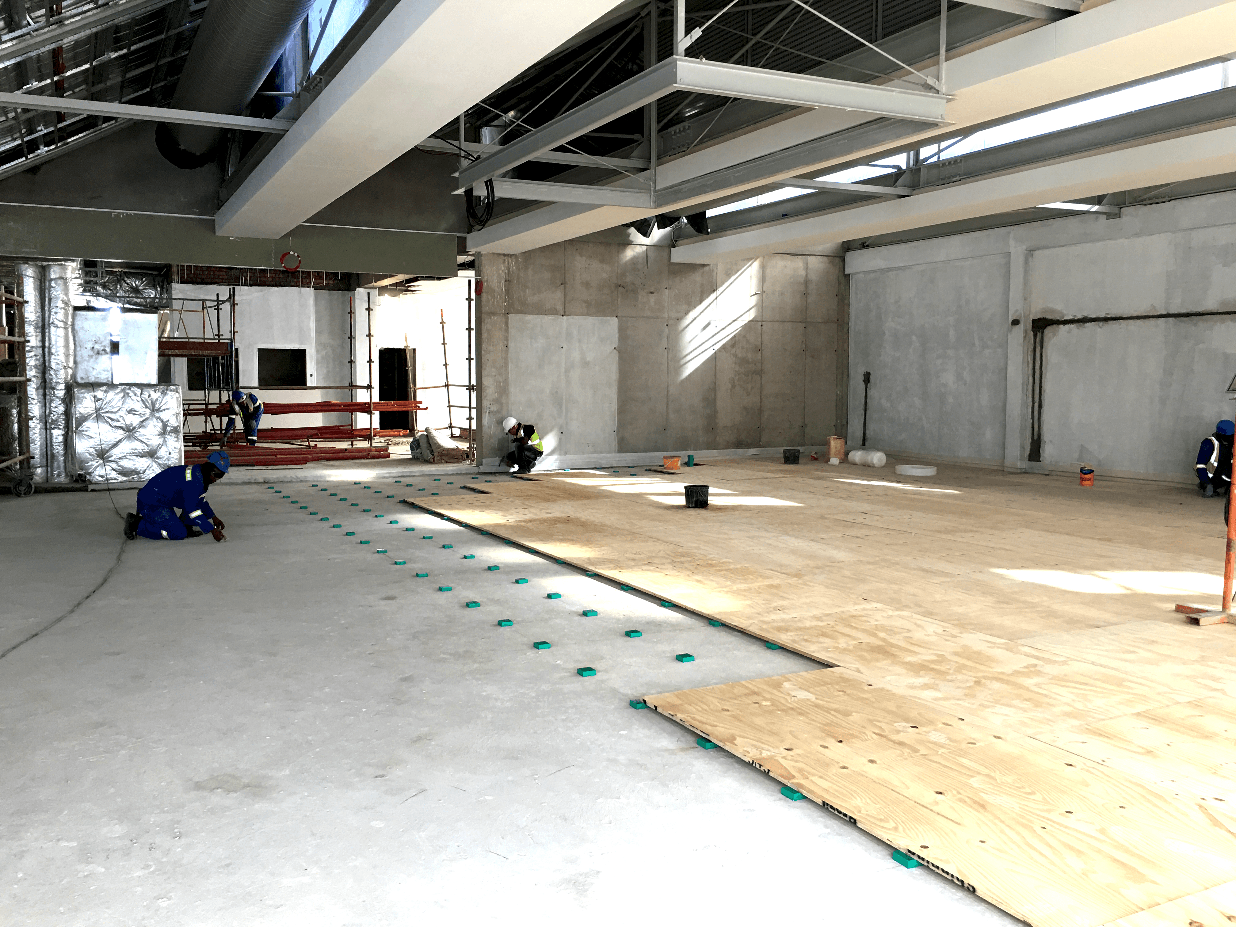 AMC acoustic floor blocks being installed on a concrete slab during gym construction